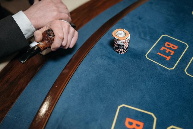 A Person Holding a Pipe Near the Gaming Table